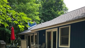 Een huis met een overdekte veranda, tuinmeubilair en een barbecue.