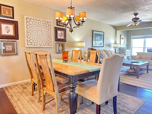 A dining room with a wooden table, chairs, and a chandelier.