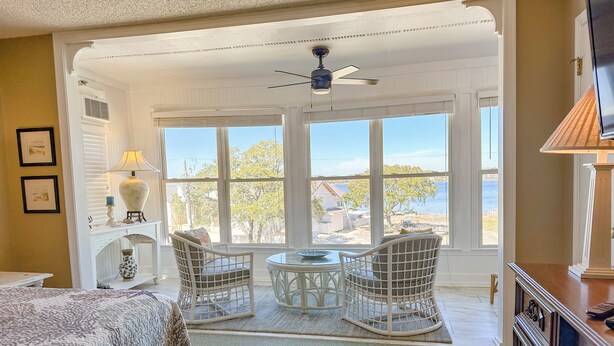 A bedroom with a bed, two wicker chairs, a small table, and a view of the beach. - L👀K!! 3 KING BEDS - Private Boat Ramp - FREE NETFLIX - Lakefront Lake Powell!!! (Panama City Beach)