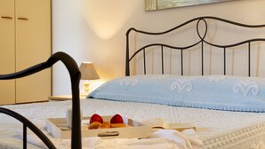 A neatly made bed with a metal headboard, a bedside table with a lamp, and a box of breakfast items. - VILLA IPPOCAMPO private pool and close to the sandy beach (Capo Coda Cavallo)