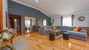 Una sala de estar moderna con un sofá gris, piso de madera y un espejo grande.