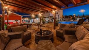 Un patio al aire libre con mobiliario de mimbre, una piscina y un comedor con dardos.
