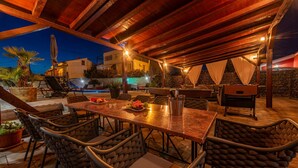 Un patio exterior con piscina, zona de comedor y sillones de descanso.