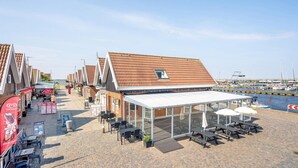 Een café aan zee met terras, een overdekt terras en uitzicht op de jachthaven.