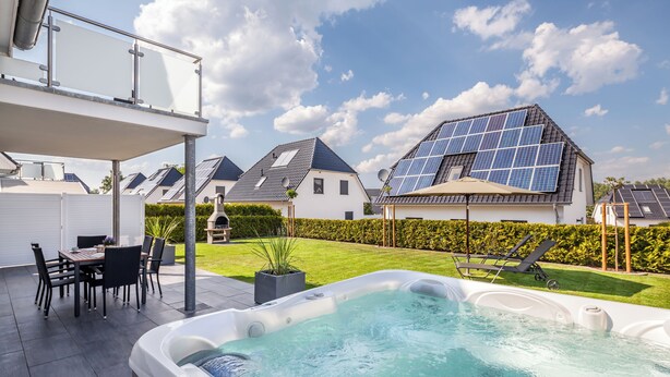 A residential area with a hot tub, outdoor seating, and solar panels on the roofs. - Villa Dalu am See - 5* luxury vacation home (Göhren-Lebbin (OT Untergöhren))