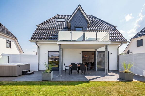 A modern house with a covered patio, a hot tub, and a garden.