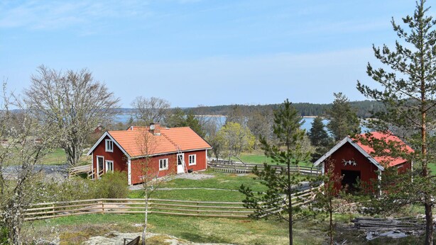 A red barn with a sloped roof and a fenced area in front.