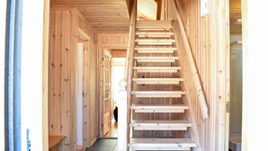Interior de madera con una escalera central que conduce a pisos superiores.