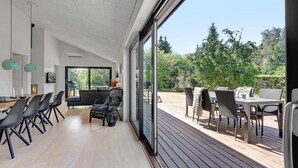 Un interior moderno con comedor, chimenea y un patio con mobiliario exterior.