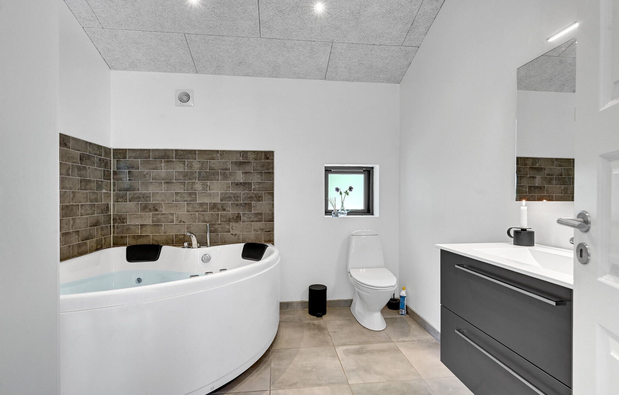 A modern bathroom with a freestanding bathtub, a toilet, and a vanity with a mirror.