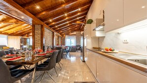 A modern kitchen with a wooden ceiling, a dining area with a long table set for a meal, and a view into the living area. - Beautiful home in Turanj with sauna (Turanj)