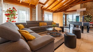 A modern living room with a sectional sofa, a coffee table, and a foosball table. - Beautiful home in Turanj with sauna (Turanj)