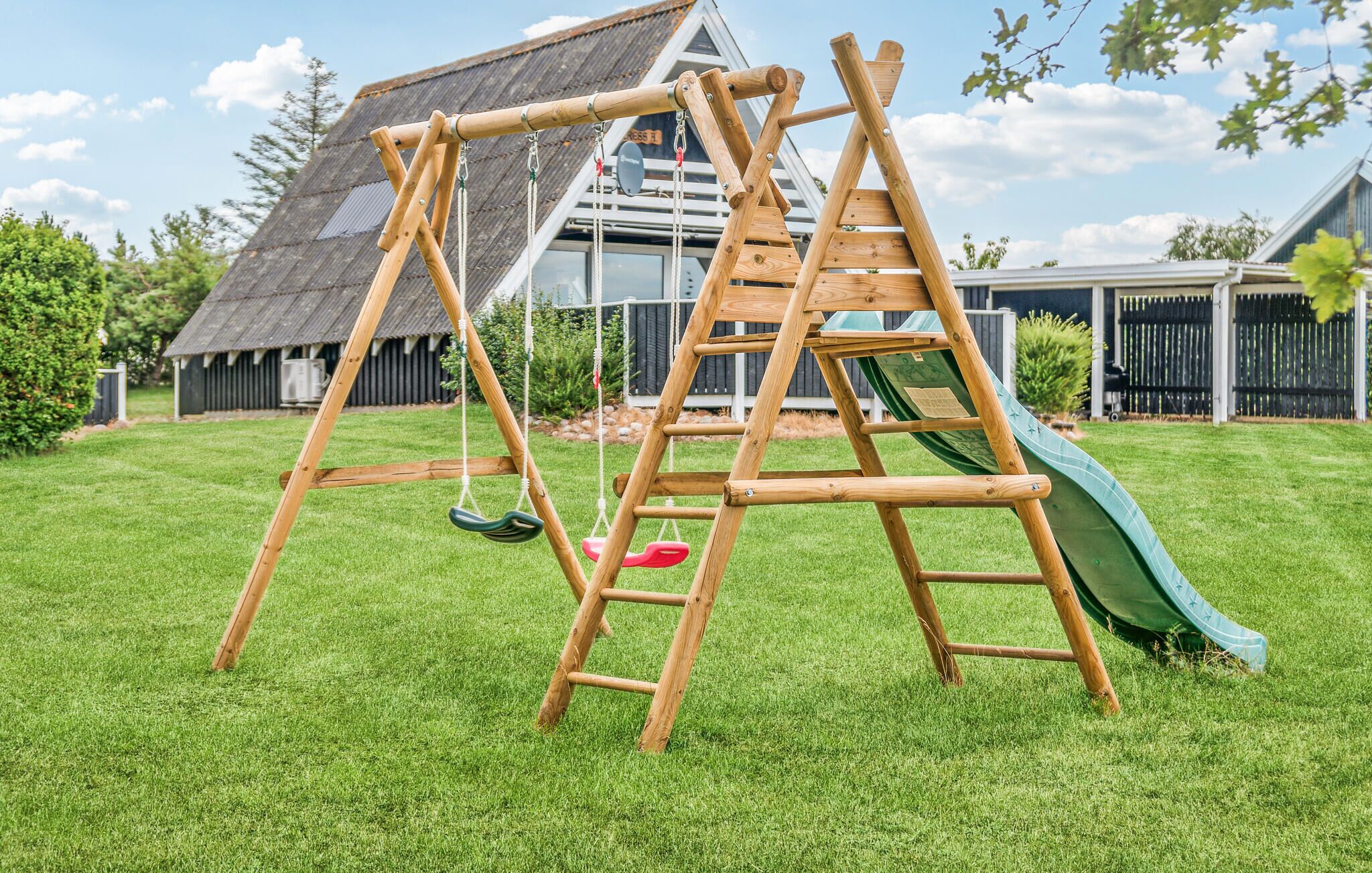 A wooden swing set with a slide in a backyard.