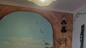 A room with a mural of a beach scene, a hanging light fixture, and a potted orchid.