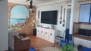 A living room with a mural, a sofa, a TV, a cabinet, and a washing machine.