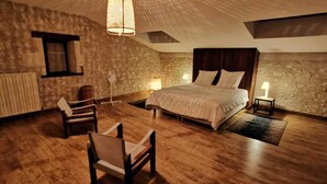 A cozy bedroom with a large bed, a chair, a small table, and a hanging light fixture. - Pretty stone house with swimming pool in magnificent agricultural area (Bonnes)