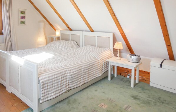 A bedroom with a bed, bedside table, lamp, radio, and a dresser.