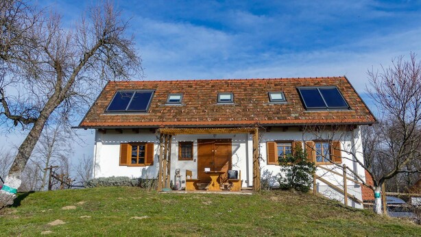 A two-story house with a sloped roof, a front porch, and a small garden area.