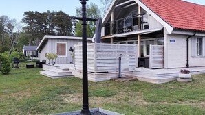 Ett tvåvåningshus med ett rött tak, en inglasad veranda och en liten terrass.