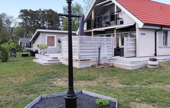 Ett tvåvåningshus med ett rött tak, en inglasad veranda och en liten terrass.