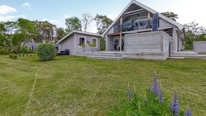 Ett modernt hus i två våningar med en stor veranda och en täckt uteplats med sittplatser.