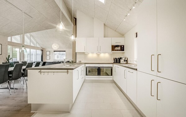 A modern kitchen with white cabinetry, a central island, and pendant lighting. - Nice home in Blåvand with sauna (Blåvand)
