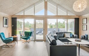A spacious living area with a large sliding glass door leading to an outdoor patio, a modern sofa set, and a dining table. - Nice home in Blåvand with sauna (Blåvand)
