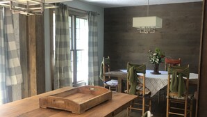 A modern kitchen with a wooden countertop, a dining table with chairs, and a hanging light fixture. - Unique home in great neighborhood (Stroudsburg)