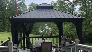 A gazebo with a table and chairs on a wooden deck, surrounded by a railing. - Unique home in great neighborhood (Stroudsburg)