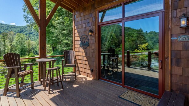 A wooden deck with outdoor seating, a glass door leading to a deck, and a sign indicating private property. - Red Wolf Chalet -Tiny Home with Eagles Nest amenities, private fire pit, pet friendly (Banner Elk)