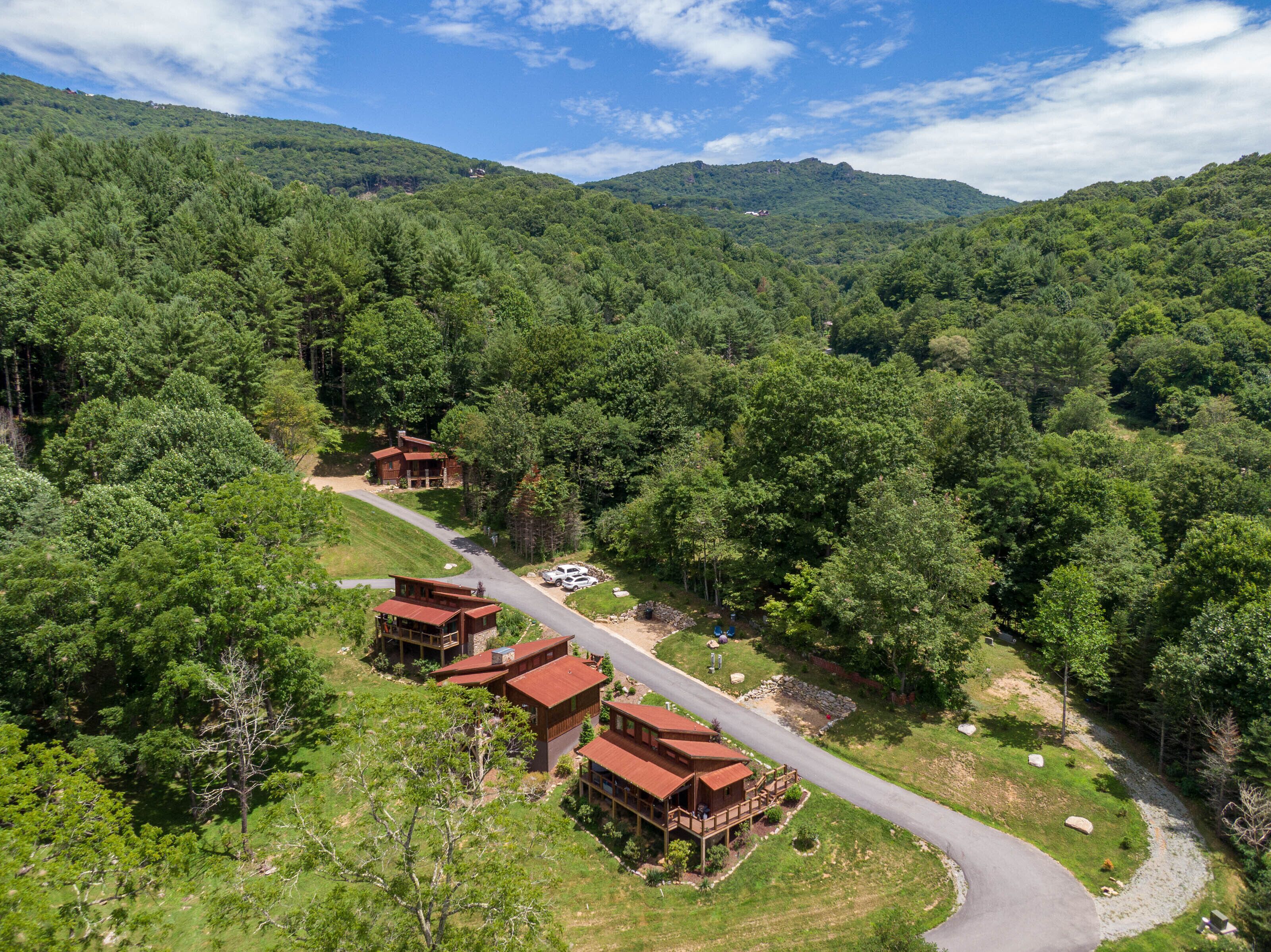 Eine Lodge mit mehreren Hütten, umgeben von dichtem Wald, einer kurvenreichen Straße und einem Berg im Hintergrund.
