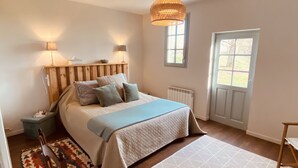 Une chambre à coucher avec un lit, des lampes de chevet, une fenêtre, un radiateur et une porte.