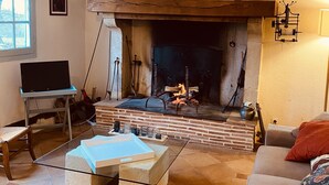 Un salon chaleureux avec une cheminée, un téléviseur posé sur un meuble et un canapé confortable.