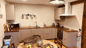 Une cuisine compacte dotée d’une table à manger ronde, d’appareils électroménagers intégrés et d’un luminaire suspendu.