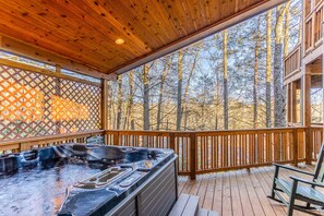 A wooden deck with a hot tub and a wooden fence.