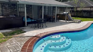 Ein Garten mit Swimmingpool, Terrassenmöbeln und einer überdachten Sitzgelegenheit.