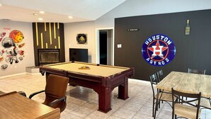 Ein Billardtisch in einem Raum mit Houston Astros Logo an der Wand, einem Hinweis auf eine Weinbar und einem Wandgemälde mit NASA-Bezug.