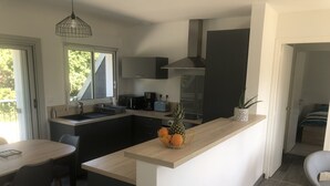 Una cocina moderna con una isla central, comedor y vistas al exterior.