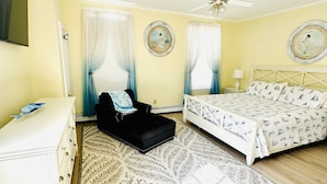 A bedroom with a bed, a chair, a dresser, and a ceiling fan.