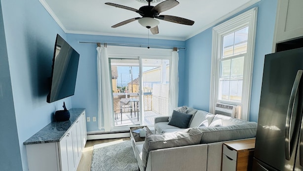 A compact kitchen with a built-in refrigerator, a ceiling fan, and a large window providing natural light.