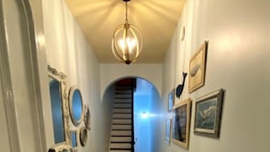 A hallway with wooden flooring, white walls, and a staircase leading to another room.
