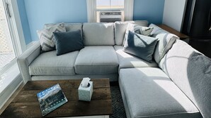 A living room with a sectional sofa, a coffee table, and a window with a view.