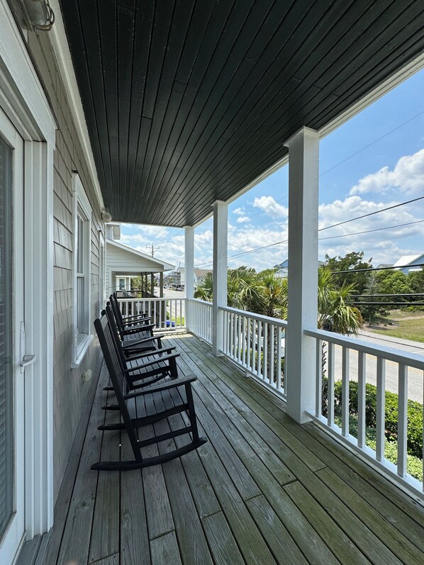 A covered porch with wooden benches and a view of a residential street.