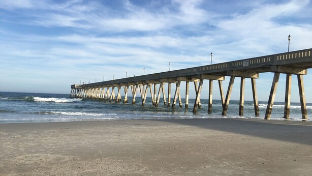 Un muelle que se adentra en el océano bajo un cielo despejado.