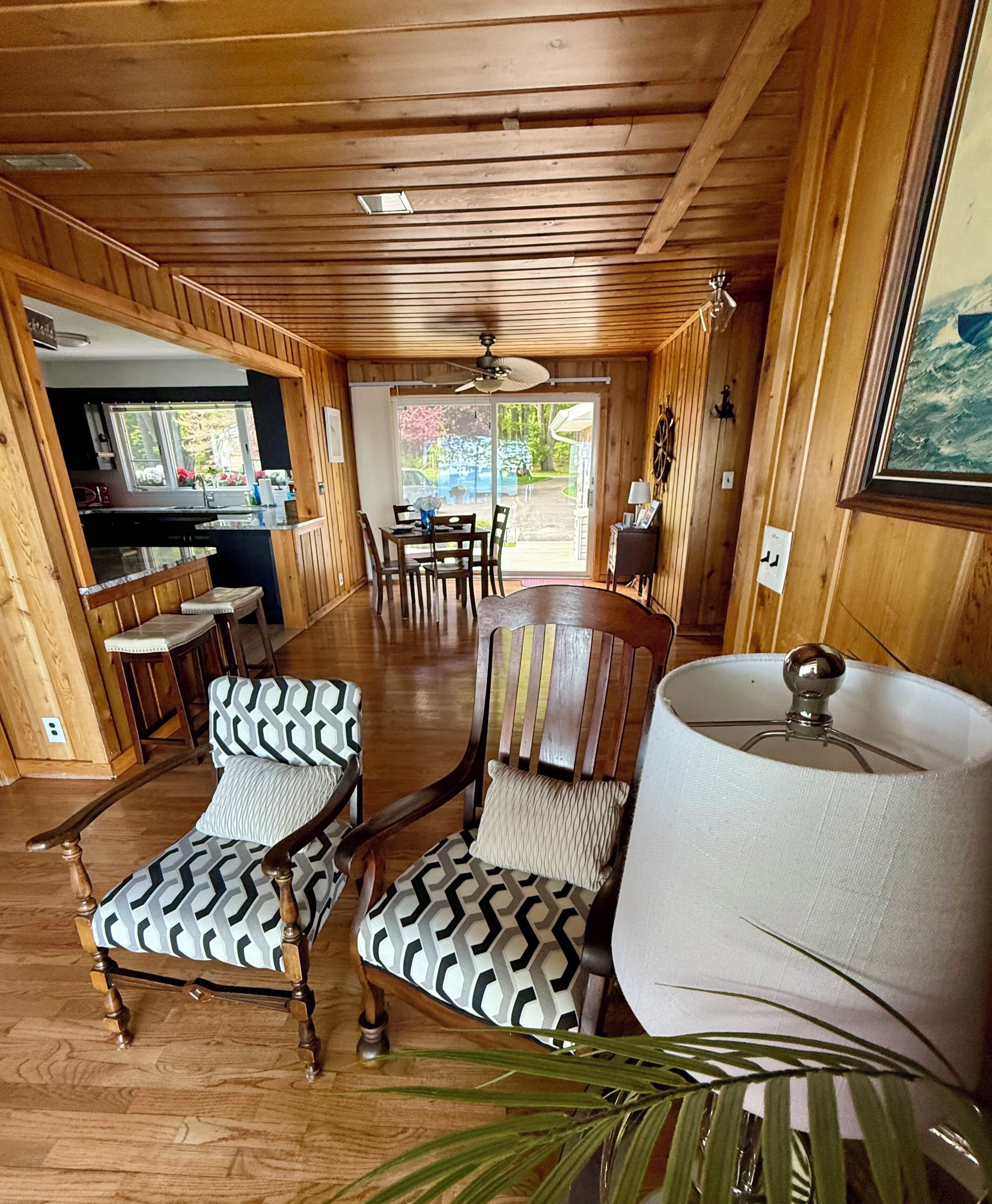 Un intérieur en bois comprenant un coin repas, deux chaises à motifs, une table et une lampe.