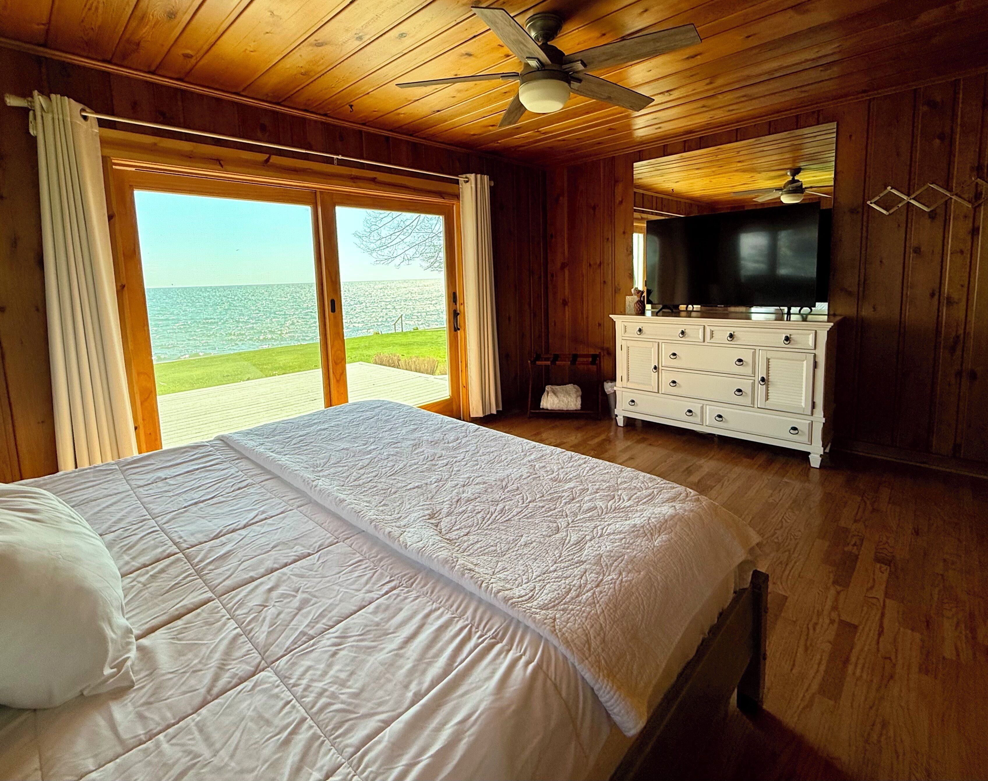 Une chambre avec un lit, une commode, une télévision et une vue sur la mer.