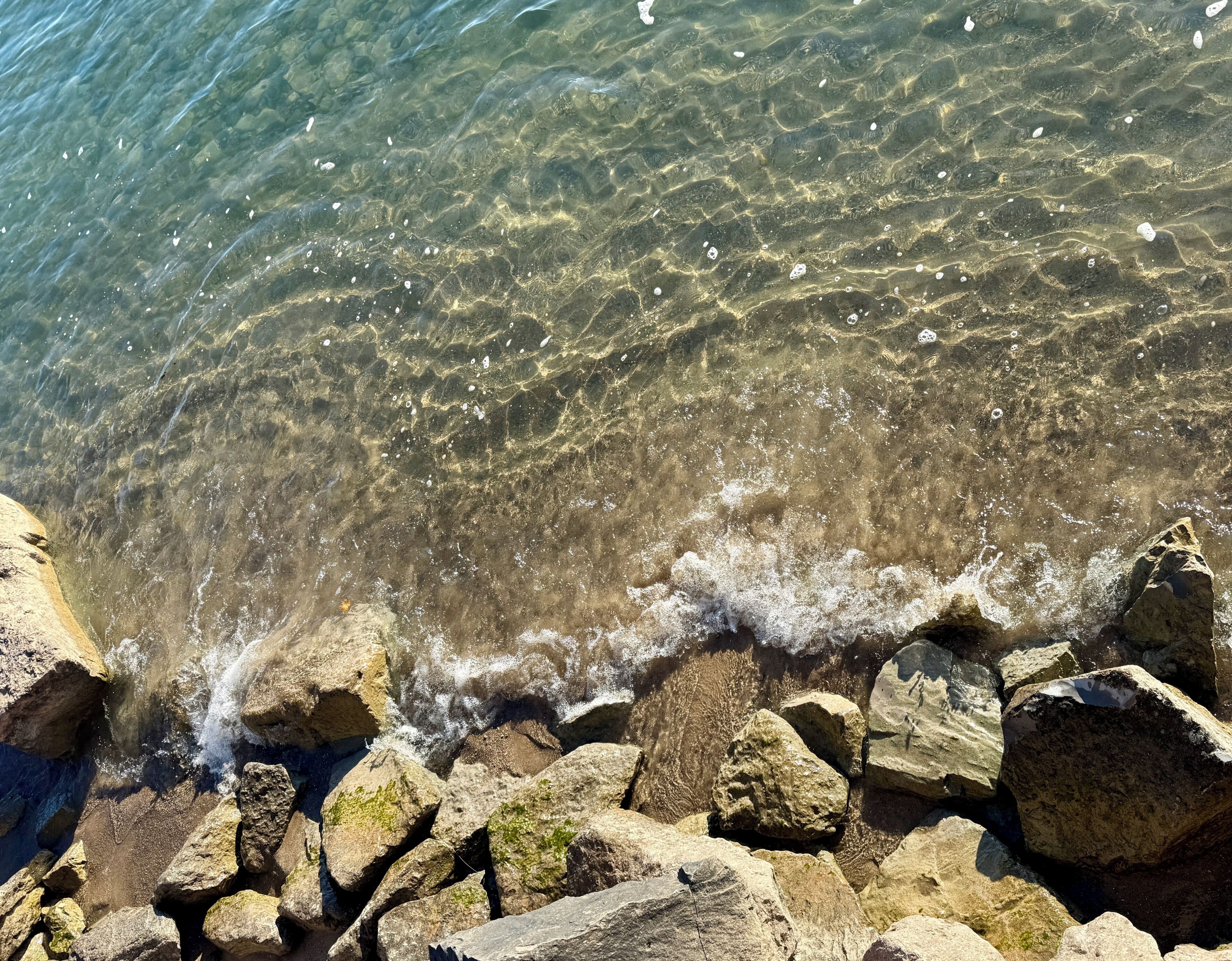 De l’eau claire, des rochers et une vague sur une plage.
