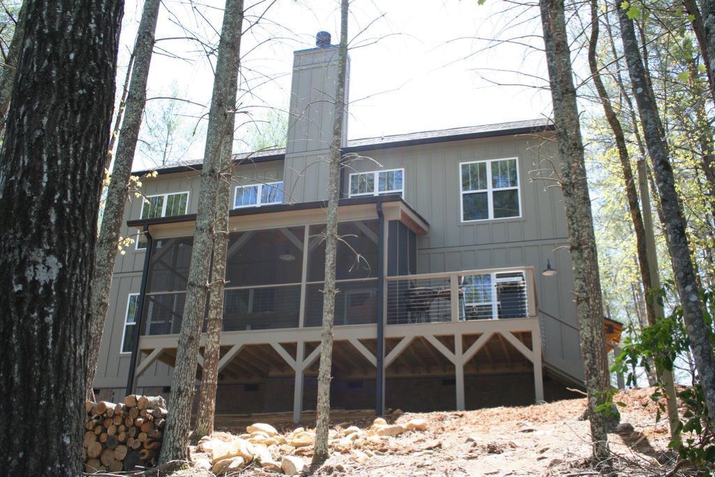 A two-story house with a covered porch, surrounded by trees.