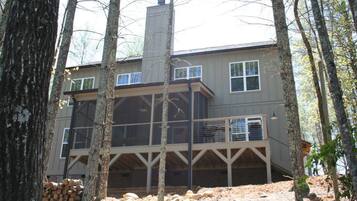 A two-story house with a covered porch, surrounded by trees.