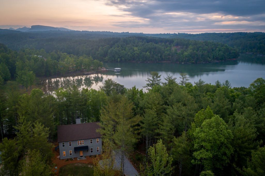 A house surrounded by dense forest and a lake.